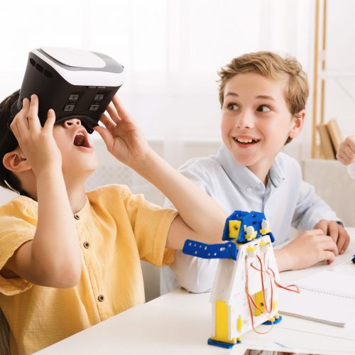 Schoolboy playing with vr glasses in classroom, having break at school